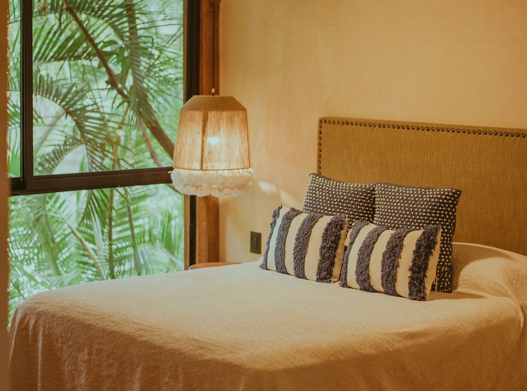 A bed made up in a room open to the palms